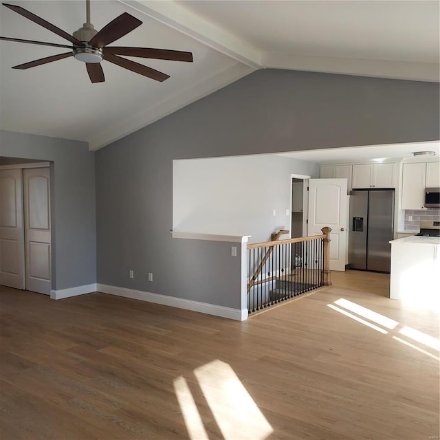 unfurnished living room featuring ceiling fan, lofted ceiling with beams, and light hardwood / wood-style floors