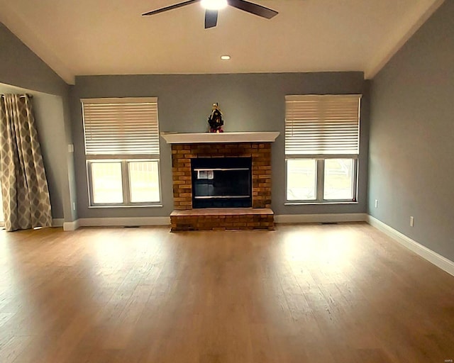 unfurnished living room with ceiling fan, a fireplace, light hardwood / wood-style floors, and vaulted ceiling