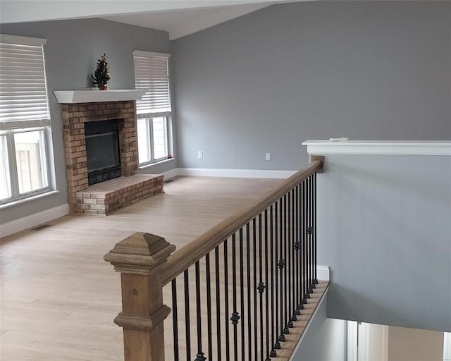 staircase with hardwood / wood-style flooring and a brick fireplace