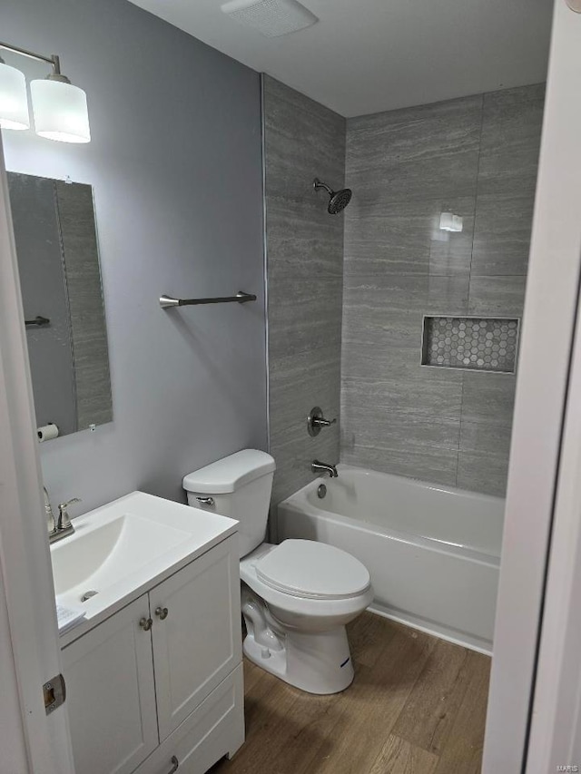 full bathroom with toilet, hardwood / wood-style floors, vanity, and tiled shower / bath