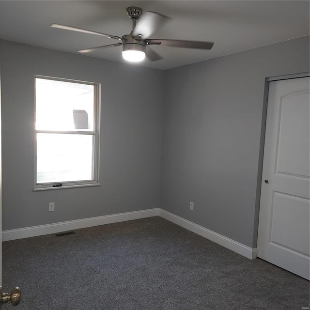 empty room with dark colored carpet and ceiling fan