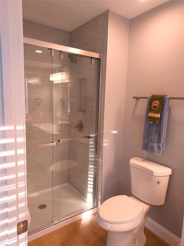 bathroom featuring hardwood / wood-style flooring, toilet, and a shower with door