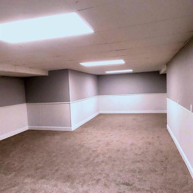 basement with a paneled ceiling and carpet