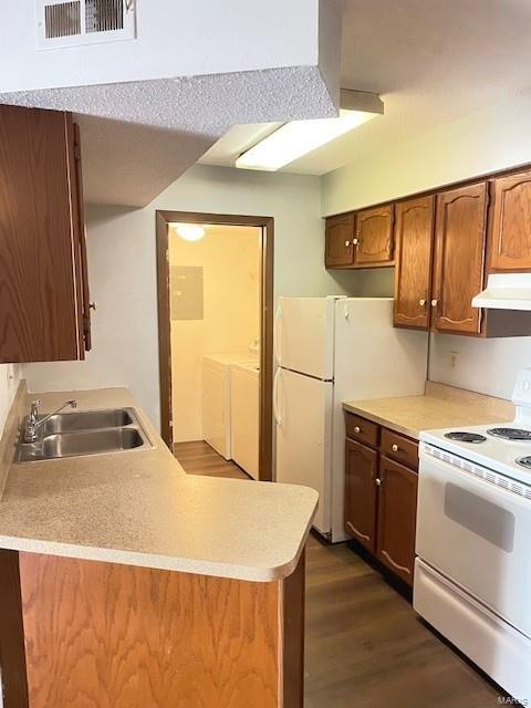 kitchen featuring dark hardwood / wood-style flooring, washing machine and clothes dryer, sink, ventilation hood, and white appliances