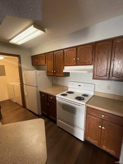 kitchen featuring white appliances, dark hardwood / wood-style flooring, and washing machine and clothes dryer