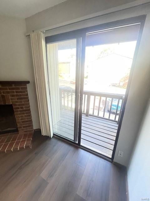 doorway featuring wood-type flooring and a brick fireplace