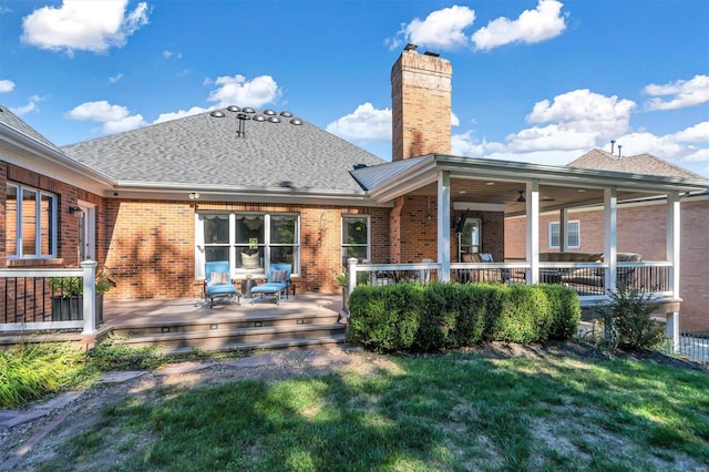 rear view of property featuring a wooden deck and a lawn