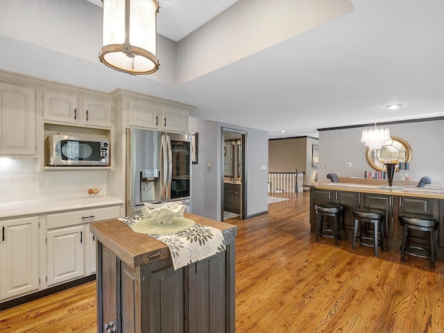 kitchen featuring a kitchen island, appliances with stainless steel finishes, white cabinets, light hardwood / wood-style floors, and tasteful backsplash