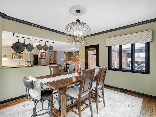 dining room featuring an inviting chandelier, ornamental molding, and light wood-type flooring