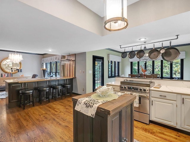 kitchen with stainless steel range, white cabinetry, light hardwood / wood-style floors, and a kitchen island