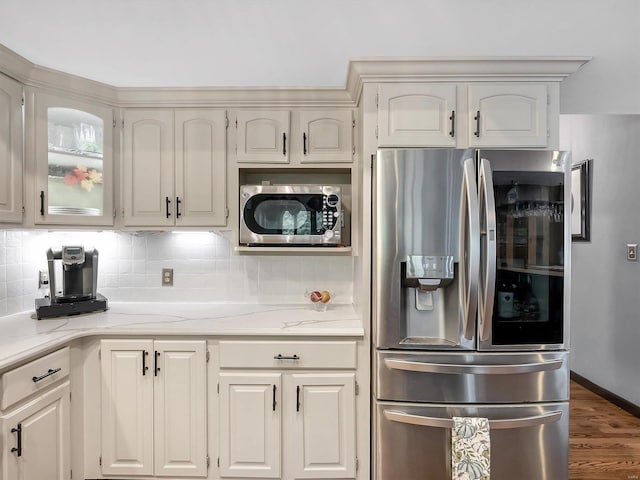 kitchen featuring backsplash, dark hardwood / wood-style flooring, stainless steel appliances, white cabinets, and light stone counters