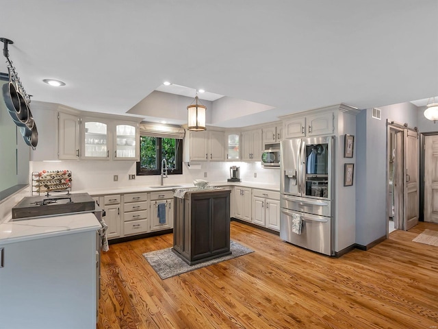 kitchen featuring a kitchen island, appliances with stainless steel finishes, white cabinetry, light hardwood / wood-style floors, and sink