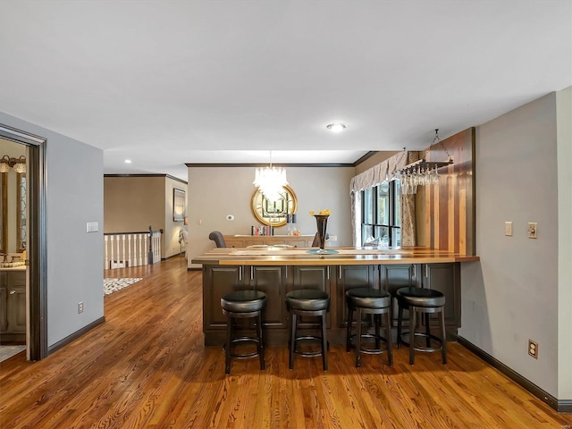 bar with crown molding, a chandelier, and dark wood-type flooring