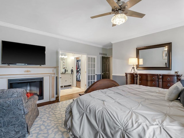 bedroom with a closet, a walk in closet, ornamental molding, light hardwood / wood-style floors, and ceiling fan