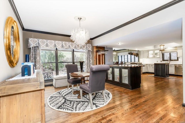 dining area with a notable chandelier, ornamental molding, hardwood / wood-style floors, and sink