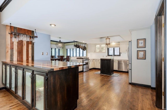 kitchen featuring pendant lighting, stainless steel appliances, dark hardwood / wood-style floors, a notable chandelier, and white cabinets