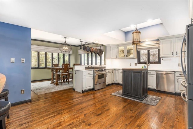 kitchen with a kitchen island, white cabinetry, appliances with stainless steel finishes, and decorative light fixtures