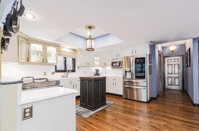 kitchen featuring white cabinetry, hanging light fixtures, a tray ceiling, a kitchen island, and stainless steel appliances