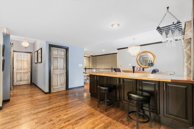 bar featuring hardwood / wood-style flooring, dark brown cabinetry, wood counters, and decorative light fixtures