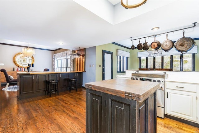 kitchen featuring white cabinetry, dark brown cabinetry, stainless steel range, a wealth of natural light, and a kitchen island