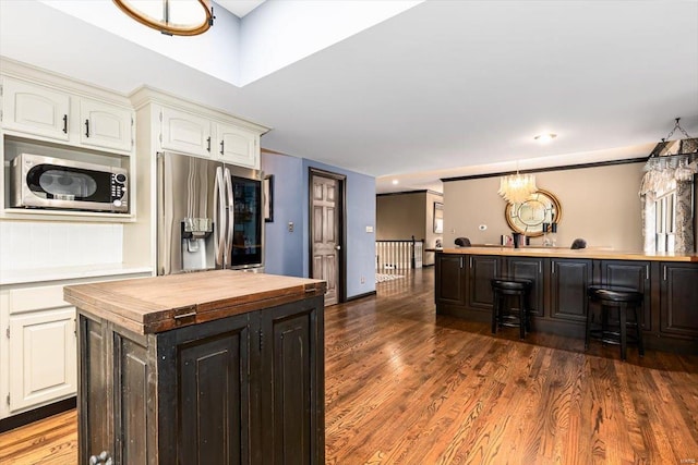 kitchen featuring wood counters, dark hardwood / wood-style flooring, a kitchen island, stainless steel appliances, and white cabinets