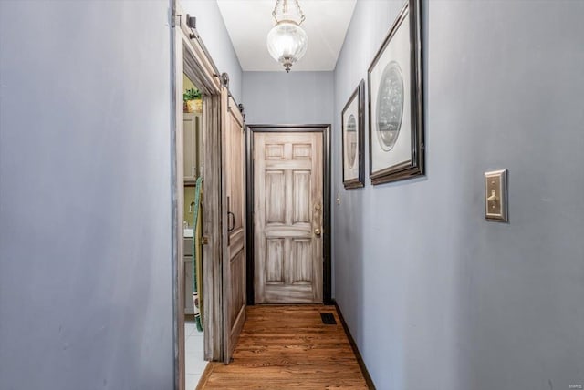 hall with a barn door and light wood-type flooring