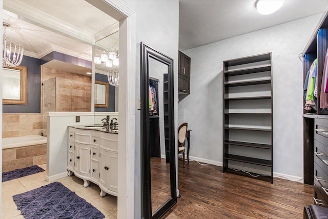 bathroom featuring hardwood / wood-style flooring, vanity, a relaxing tiled tub, crown molding, and an inviting chandelier