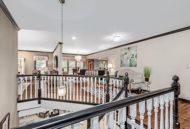 hallway with hardwood / wood-style flooring, ornamental molding, and a chandelier