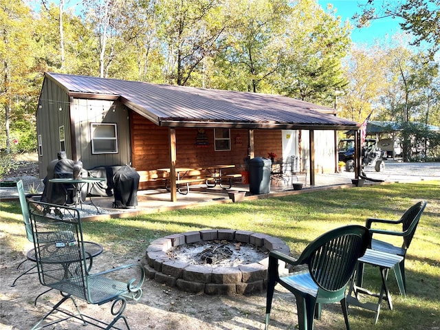 rear view of property with an outdoor fire pit, a patio, and a lawn