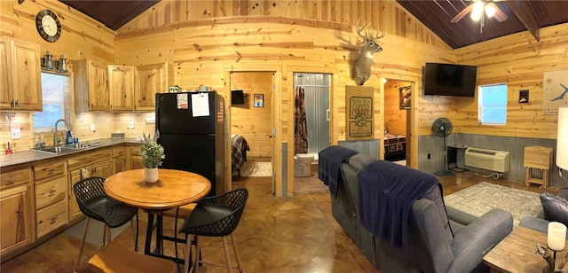 kitchen featuring sink, ceiling fan, wooden walls, high vaulted ceiling, and black refrigerator