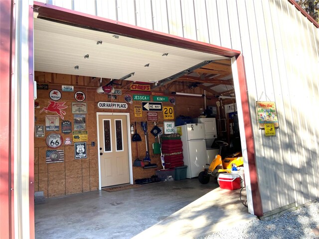 garage with white fridge and wooden walls