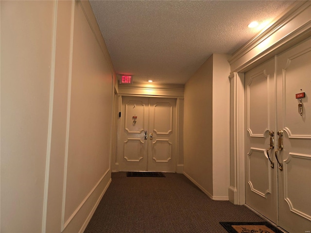 corridor with a textured ceiling and dark carpet