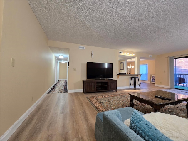 living room with hardwood / wood-style floors, a notable chandelier, and a textured ceiling