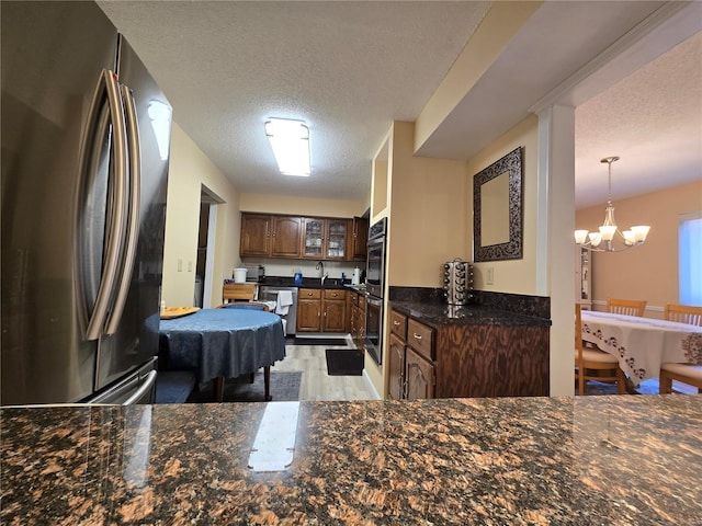 kitchen featuring hanging light fixtures, stainless steel appliances, sink, an inviting chandelier, and a textured ceiling