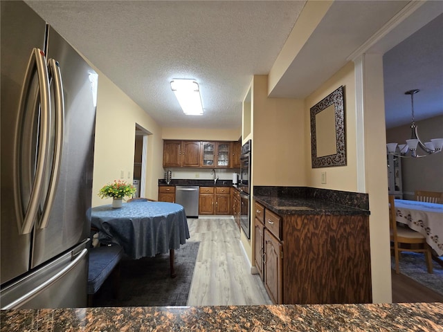 kitchen featuring stainless steel appliances, sink, light wood-type flooring, a chandelier, and a textured ceiling