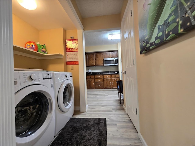 washroom featuring light hardwood / wood-style floors, a textured ceiling, and separate washer and dryer