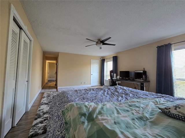 bedroom featuring a textured ceiling, multiple windows, dark hardwood / wood-style floors, and ceiling fan