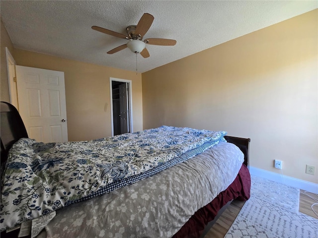 bedroom featuring a spacious closet, a textured ceiling, hardwood / wood-style floors, a closet, and ceiling fan