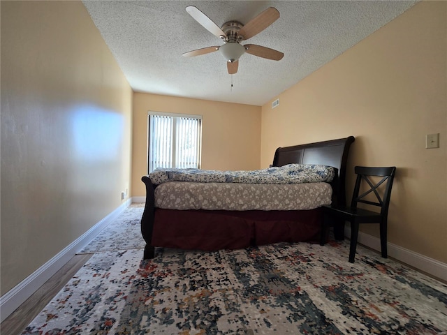 bedroom with ceiling fan, a textured ceiling, and hardwood / wood-style floors