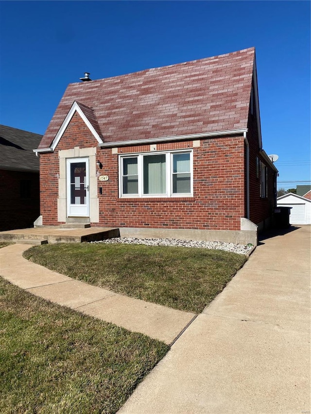 view of front of home with an outbuilding and a front lawn