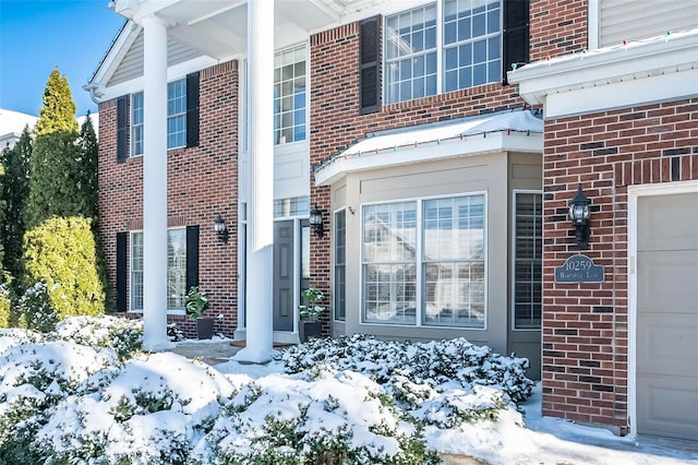 snow covered property entrance featuring a garage