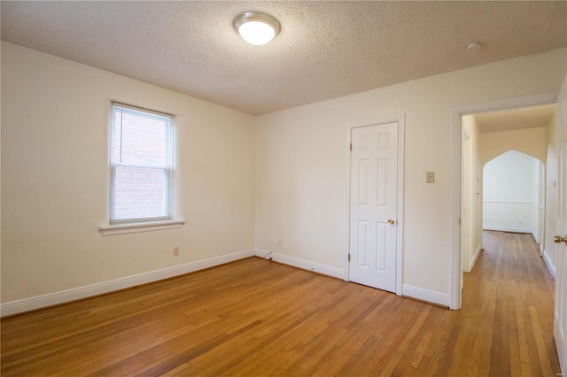 spare room with a textured ceiling and hardwood / wood-style flooring