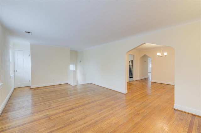 spare room featuring a chandelier and light wood-type flooring