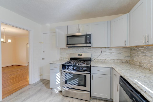 kitchen featuring a chandelier, a textured ceiling, appliances with stainless steel finishes, and light hardwood / wood-style flooring