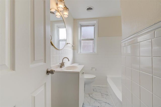 bathroom featuring a tub, vanity, tile walls, and toilet