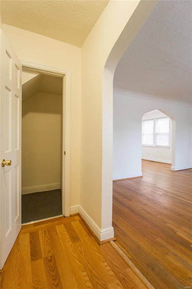 hall with hardwood / wood-style floors and a textured ceiling