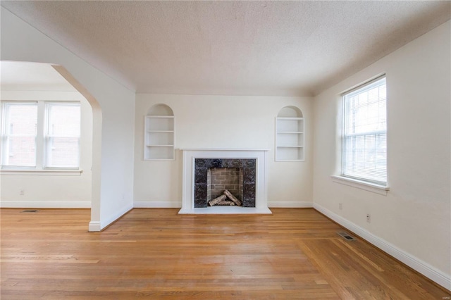 unfurnished living room with a textured ceiling, light hardwood / wood-style flooring, and a premium fireplace