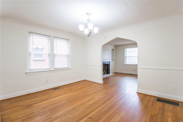 unfurnished living room featuring a textured ceiling, hardwood / wood-style flooring, and an inviting chandelier