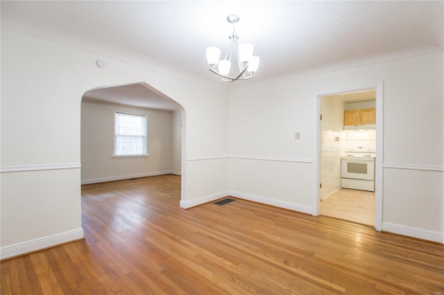 unfurnished room with a notable chandelier and light hardwood / wood-style floors