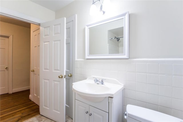 bathroom with wood-type flooring, vanity, toilet, and tile walls